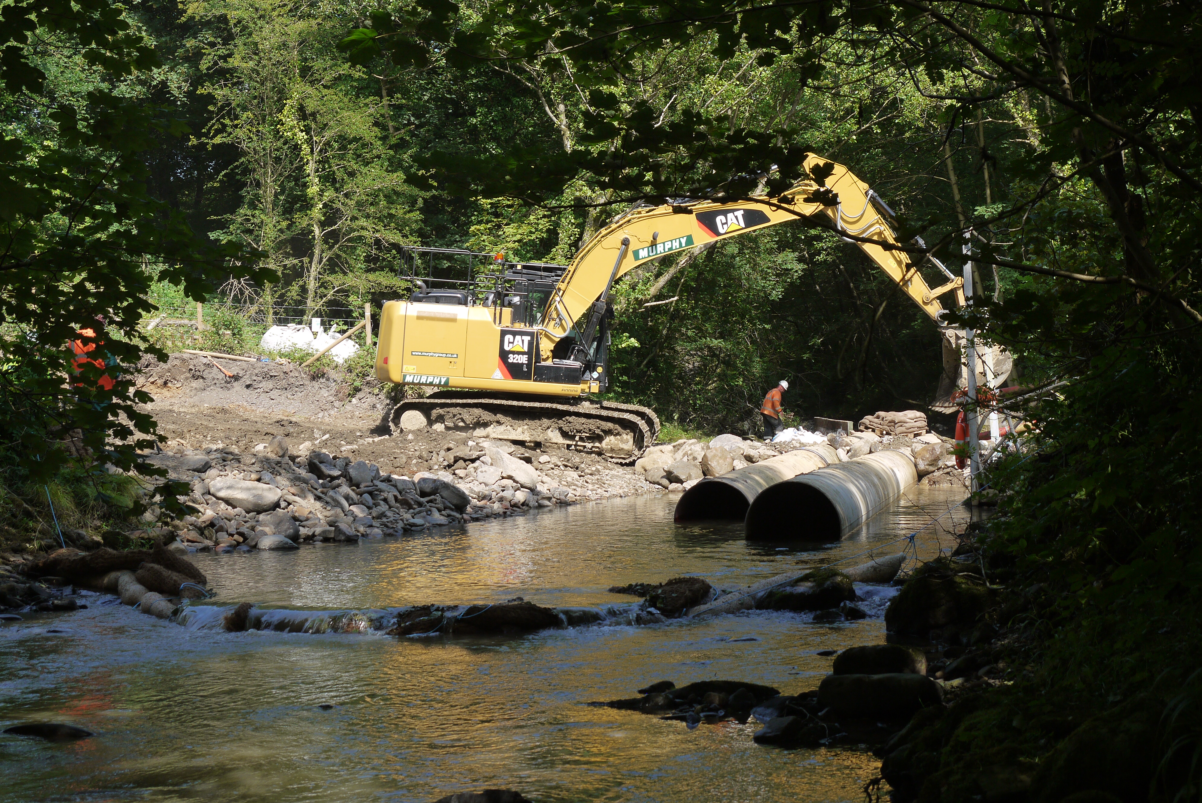 Construction work on river bank with products in river to prevent siltation of the water